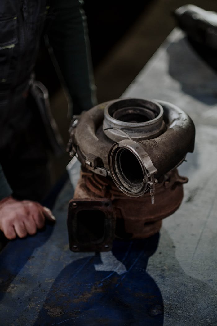 Close-up of a worn turbocharger on a workbench in an auto repair shop.